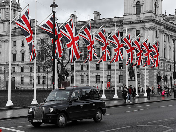 Photo of Black UK taxi on street underneath row of British flags from Improving Communications UK.